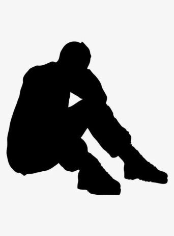 A worried man stressed sitting on his butt during the day on white ground in studio shot with his head between his hands because of having problems in desperate situation under stress
